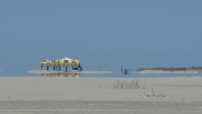 Paviljoen Paal 3 als een fata morgana aan de horizon op het strand
