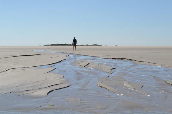 man op het strand bij afwaterende mini-delta