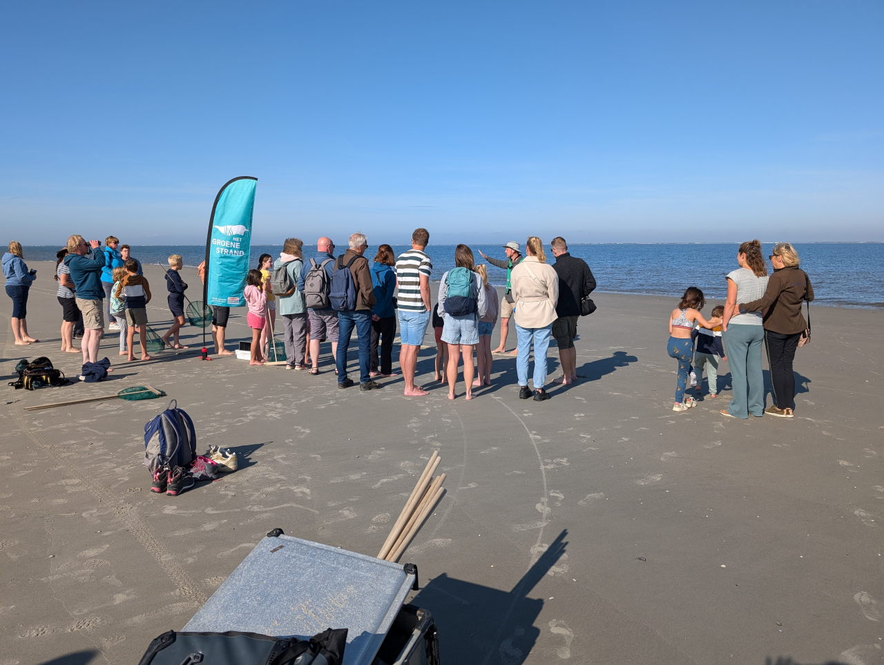 kinderen en volwassenen luisteren naar instructies op het strand