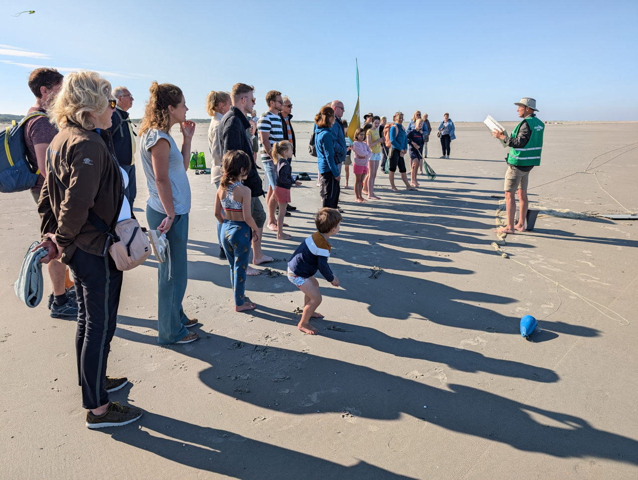 kinderen en volwassenen luisteren naar instructies op het strand