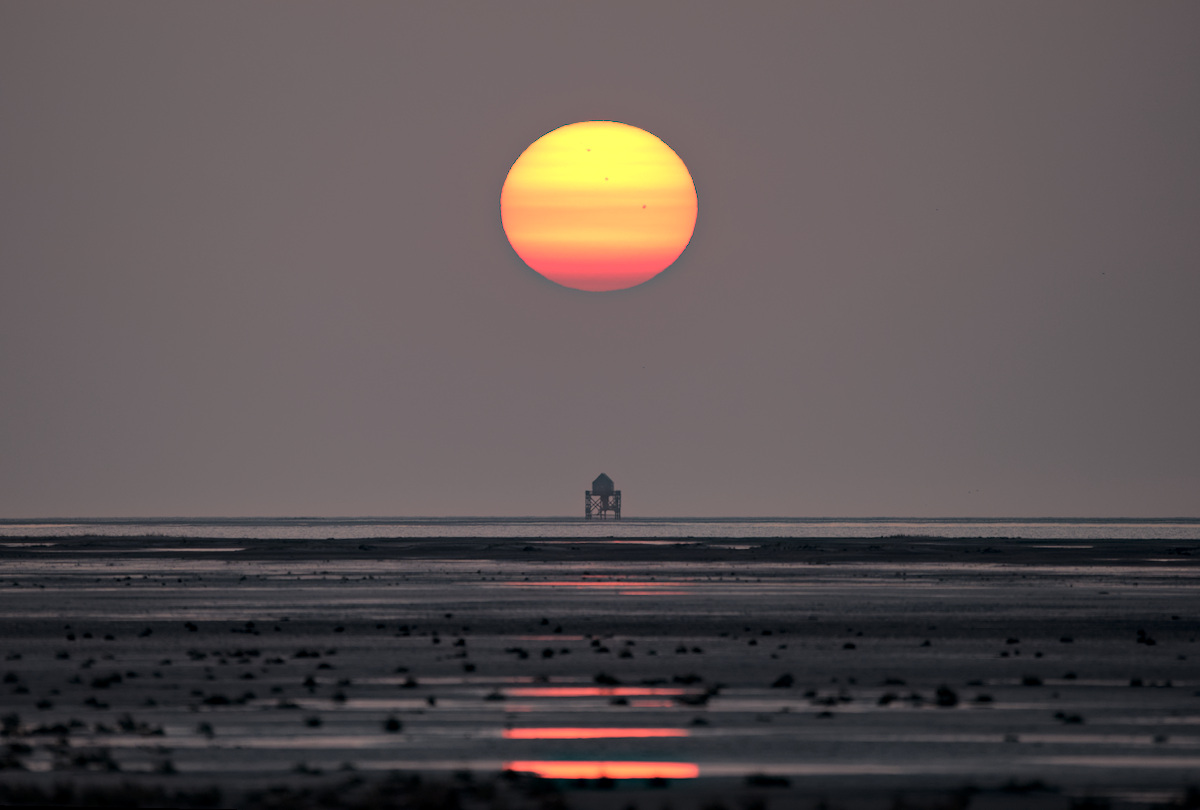 laaghangende zon boven drenkelingenhuisje aan de horizon