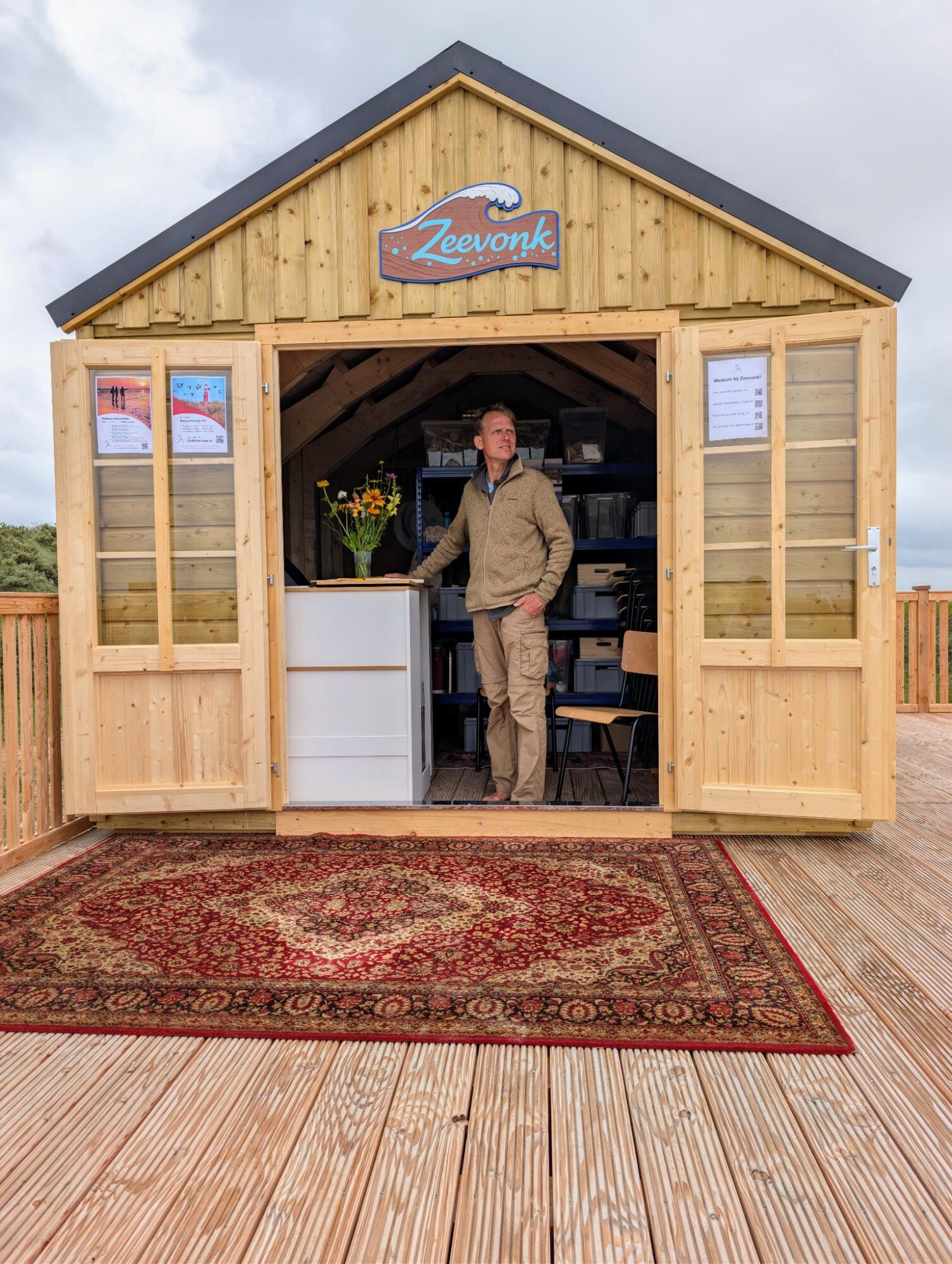 Man in de deuropening van strandhuis met opschrift Zeevonk
