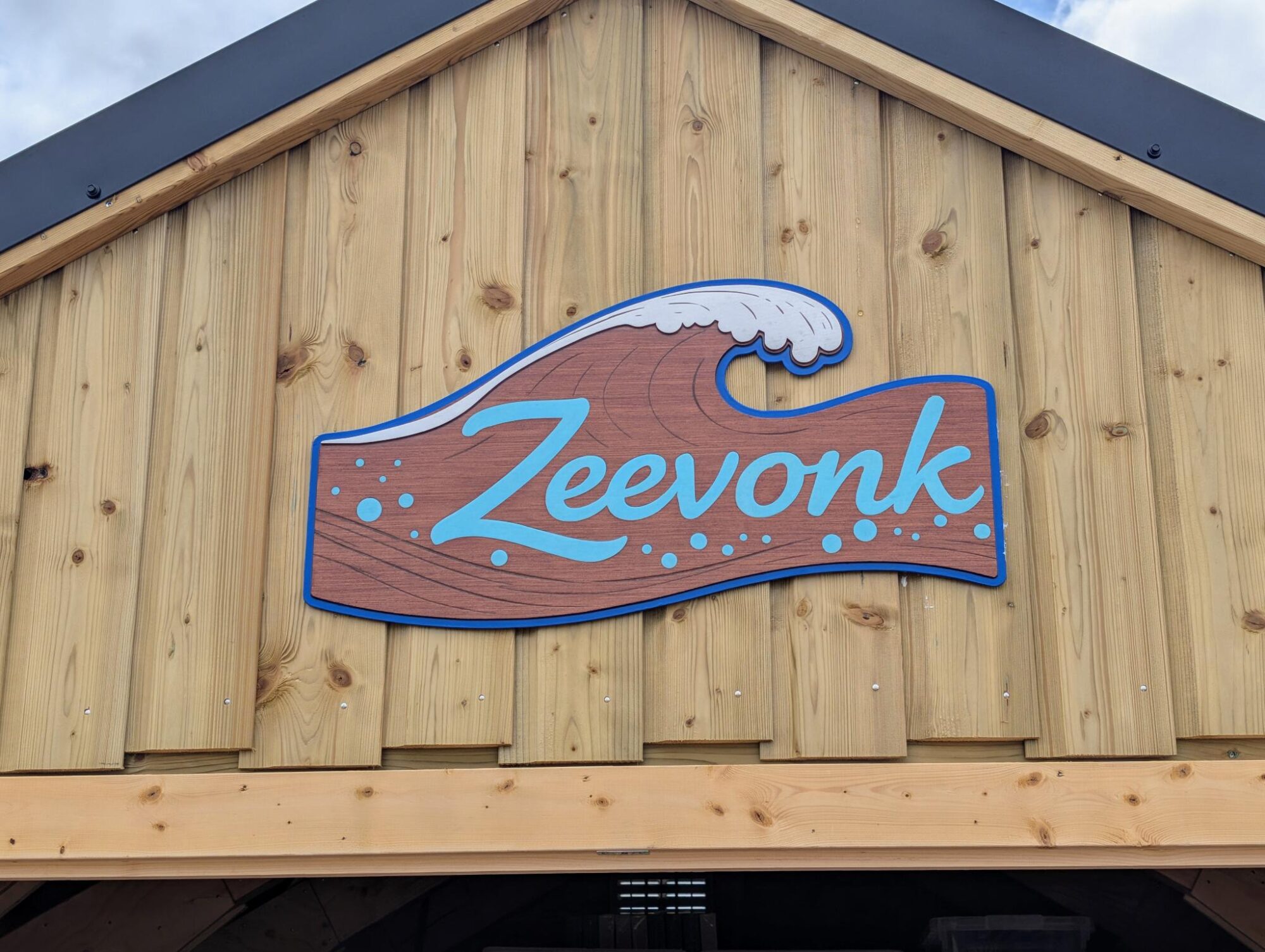 Houten bord in de vorm van een golf met opschrift Zeevonk