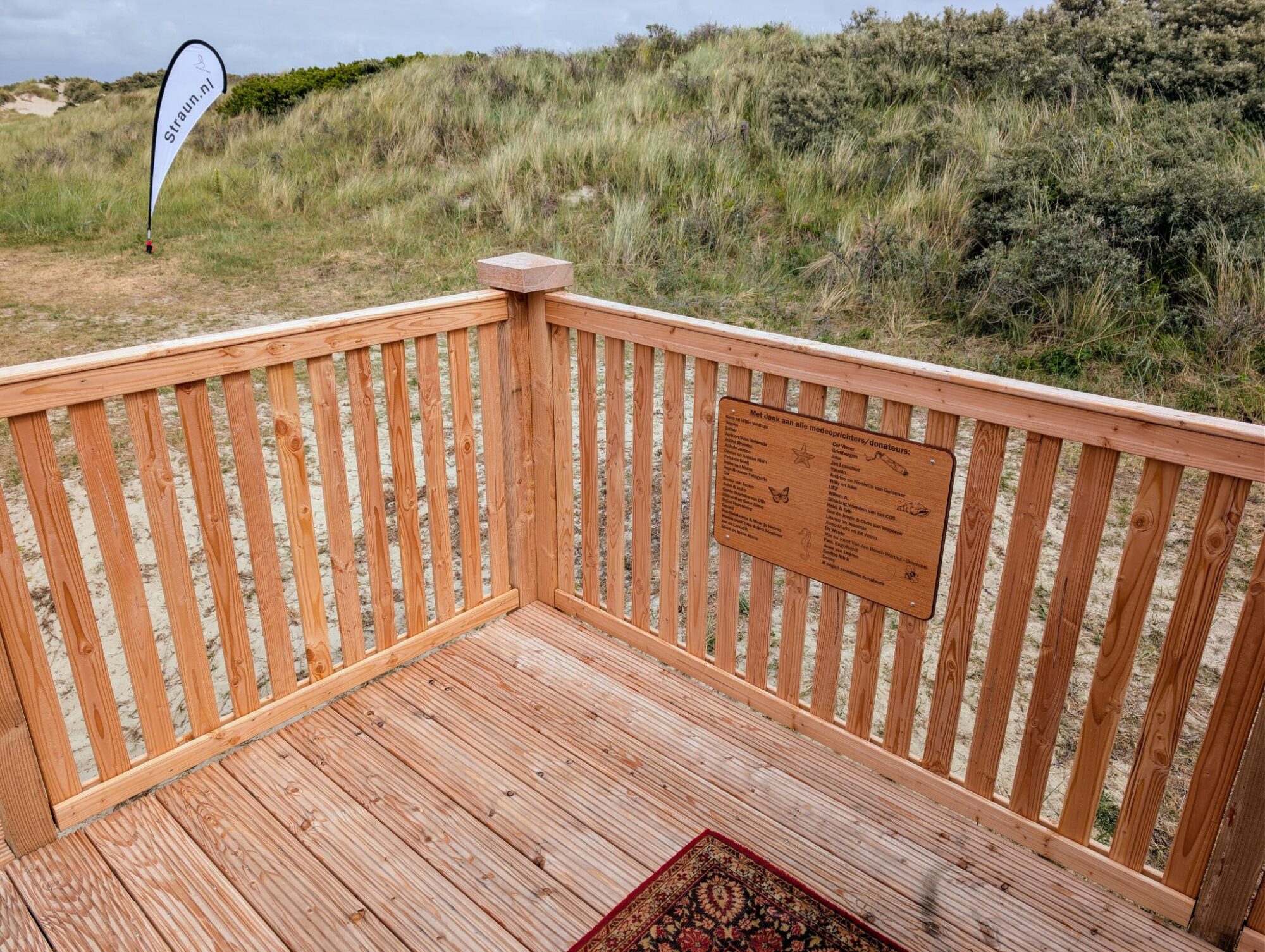 balustrade met houten plaquette en vlag in de verte