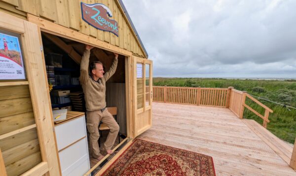 Man in deuropening van strandhuis Zeevonk